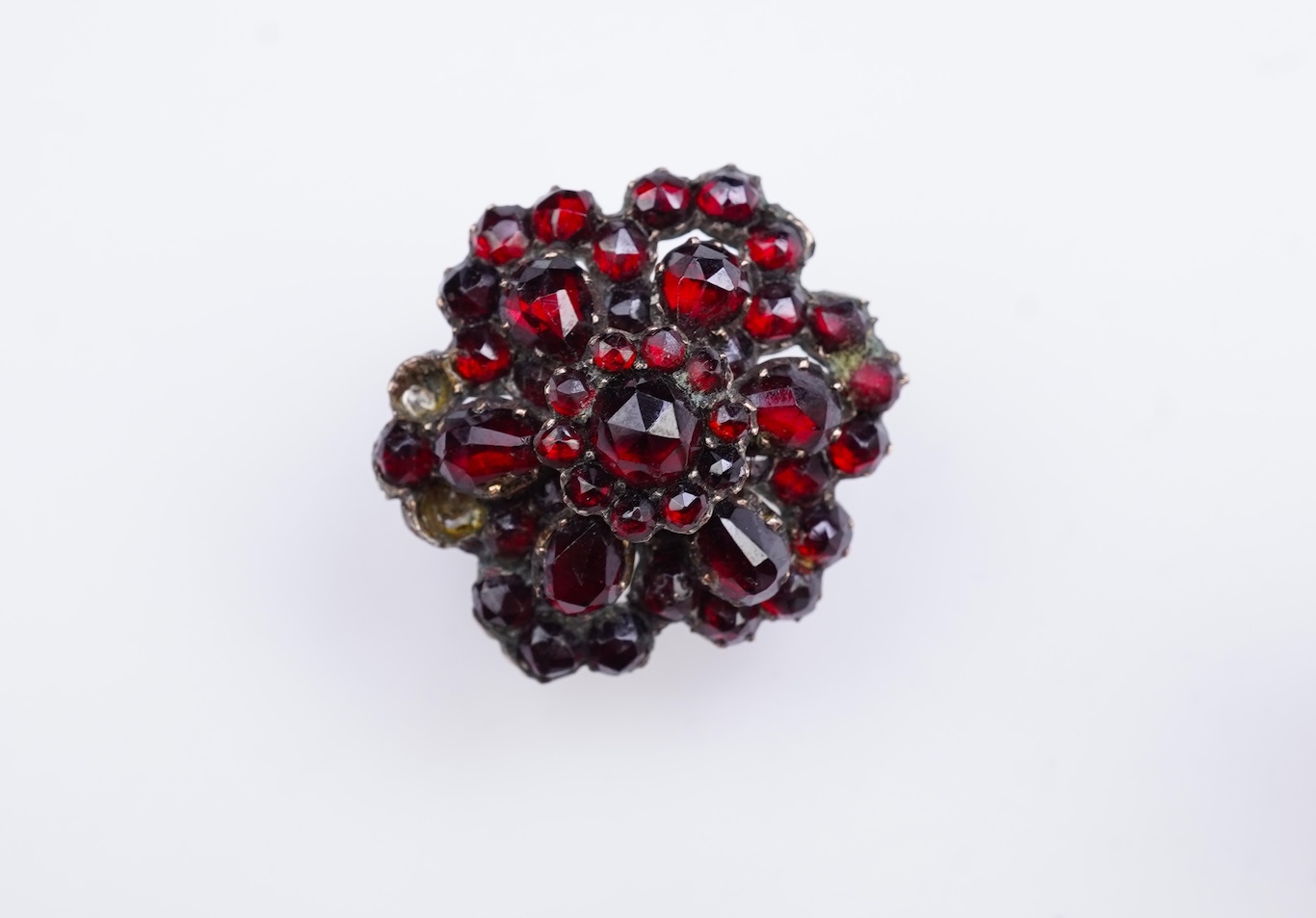 A suite of garnet and paste jewellery, comprising: a brooch, 5cm diameter; a bangle, inner circumference 16cm; two rings, sizes I and M; a pair of earrings, and a single earring, each set with rose-cut garnets; and a pai
